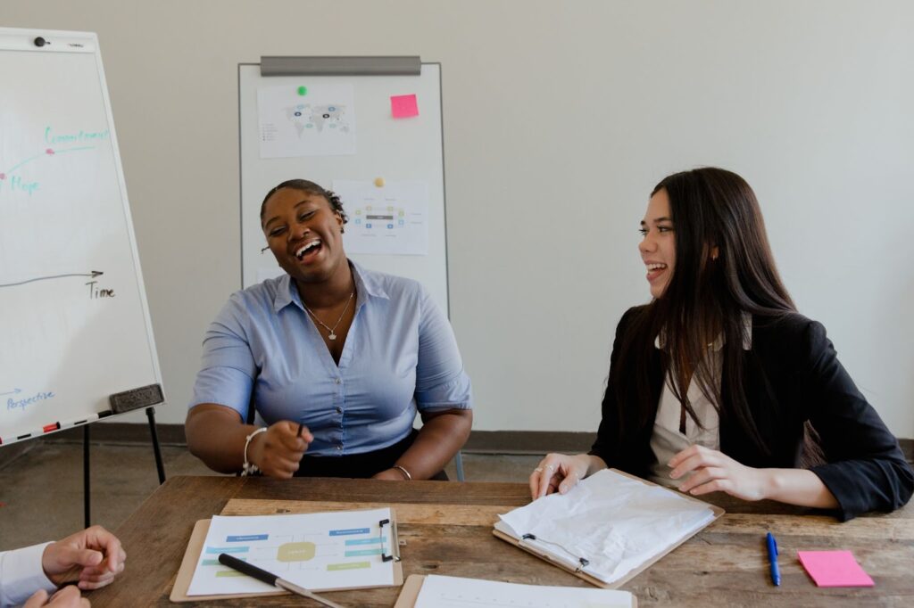 Women Laughing at a Table With Work Documents