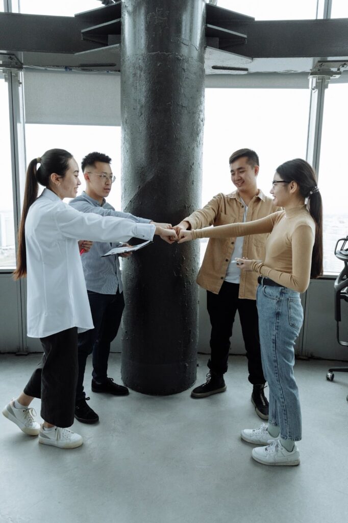 A group of people standing and sharing a moment of success, expressing unity with a fist bump.