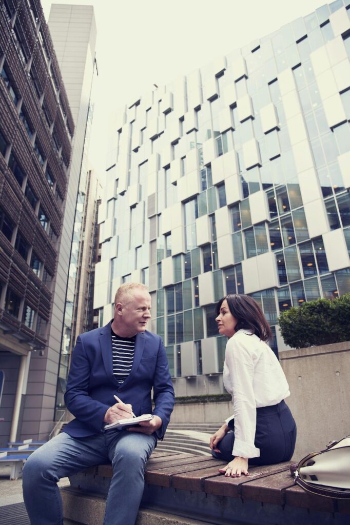 Two People Speaking Outside a Building