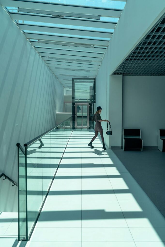 Woman Walking in Glass Hallway with a Handbag