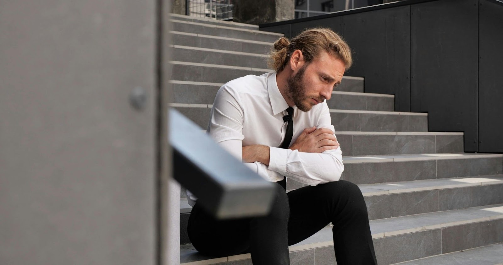 A business person sitting down on the stairs looking preoccupied