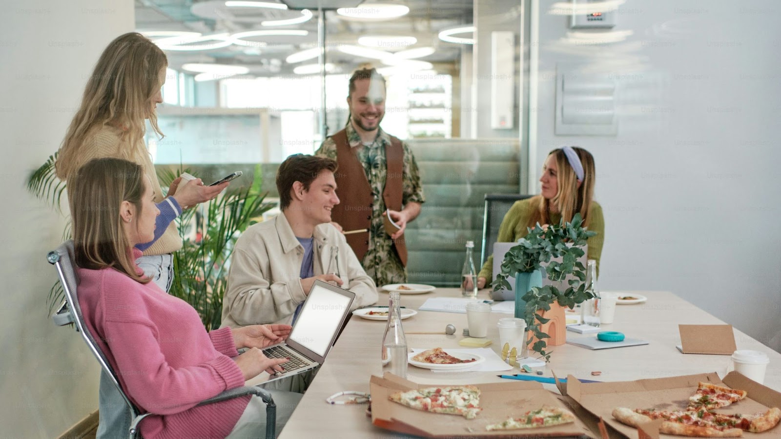 A group of people at an office relaxing and having some pizza together