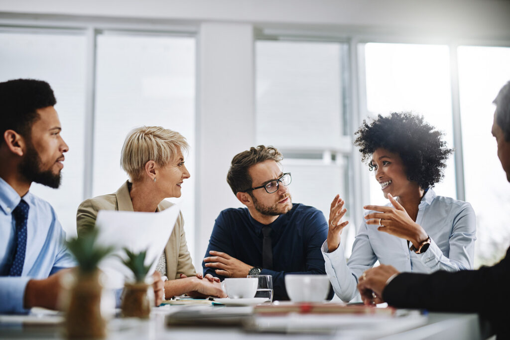 A group of smiling people having a meeting around a boardroom table.