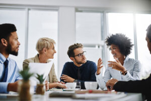 A group of smiling people having a meeting around a boardroom table.
